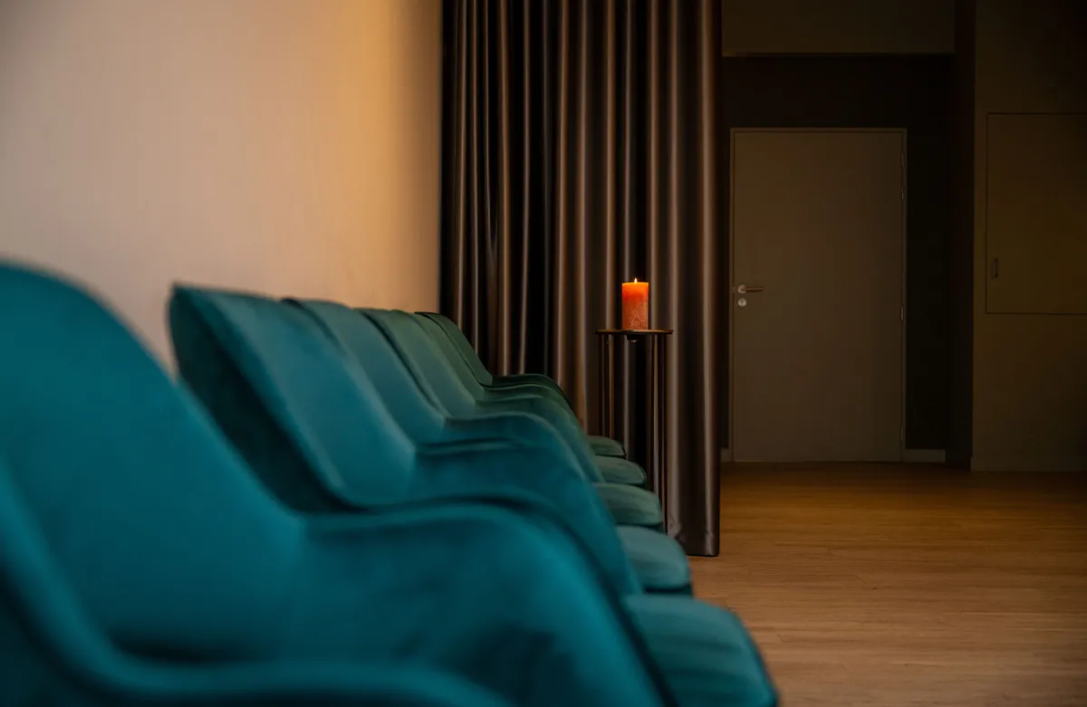 Rij groene fluwelen stoelen met een brandende kaars voor een donker gordijn